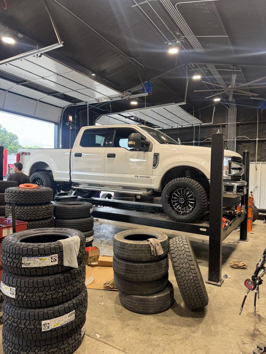White Ford Super Duty lifted on rack in our shop bay